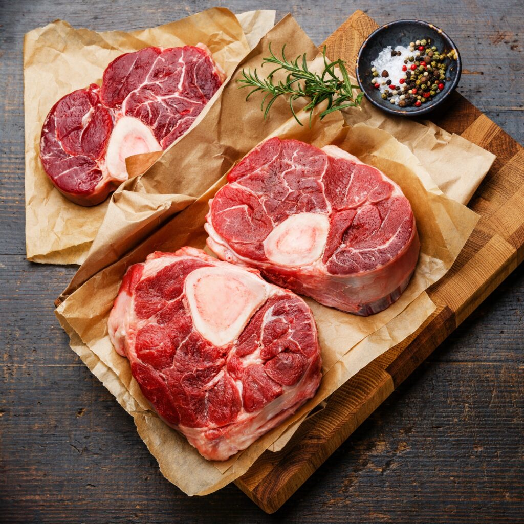 raw fresh cross cut veal shank and seasonings for making osso buco on wooden cutting board